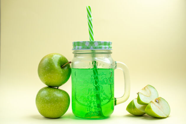 鸡尾酒正面图绿色苹果汁罐内有新鲜苹果 饮料上有白色水果鸡尾酒的照片前面新鲜水果