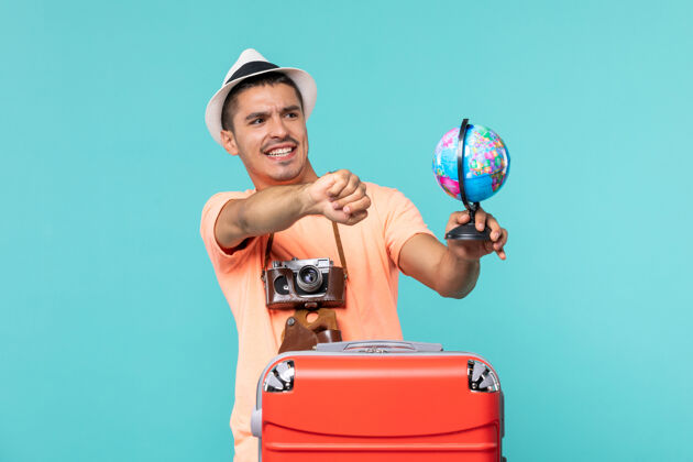 相机在度假的男人拿着地球仪和蓝色的相机成人举行旅行