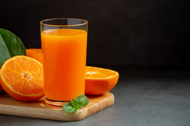 挤压新鲜的橙汁在黑暗的背景玻璃液体切割木头