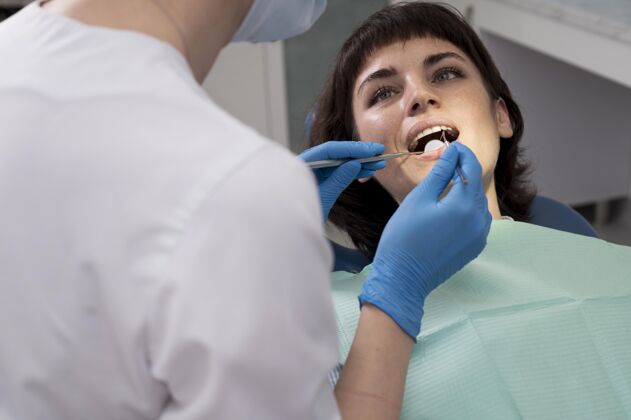 面罩年轻的女病人在正畸医生那里做牙科手术职业雇员工人