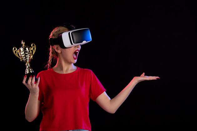 人物年轻女性在黑暗的墙上玩虚拟现实和赢得奖杯的正面视图赢家游戏人物