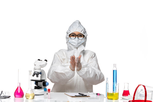外套正面图身着特殊防护服的年轻女化学家在白色办公桌上微笑鼓掌病毒实验室covid健康化学特殊鼓掌化学