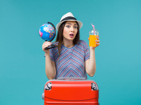 微笑前景度假妇女手持果汁和地球仪在蓝色背景上海上旅行度假暑假旅行旅程地球仪举行