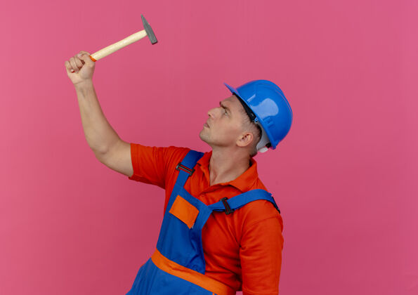 建筑工人站在剖面图上年轻的男建筑工人穿着制服 戴着安全帽 抬起头看着锤子站立年轻安全
