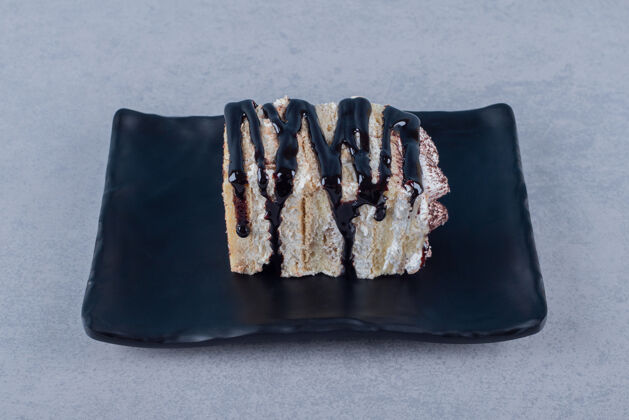 烹饪新鲜出炉的蛋糕片和巧克力酱放在黑色盘子里美味高树叶