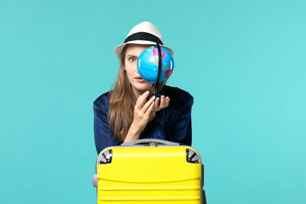 旅程正面图年轻女子手持地球仪 准备在蓝色背景上度假女性旅程航海飞机度假美女成人年轻女子