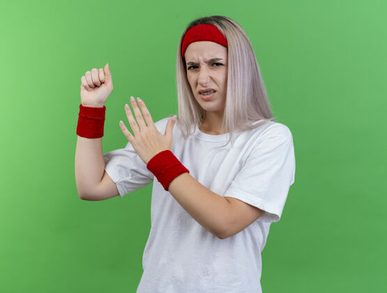 复制年轻的白人运动女孩戴着背带 戴着头带和腕带 挥舞着拳头 张开着手头带背带绿色