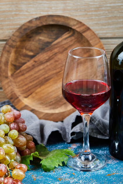 串一串葡萄 一杯红馄饨和一瓶蓝木馄饨食物木头白色