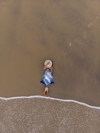 年轻一位亚洲女性躺在沙滩上的空中镜头美丽放松休闲