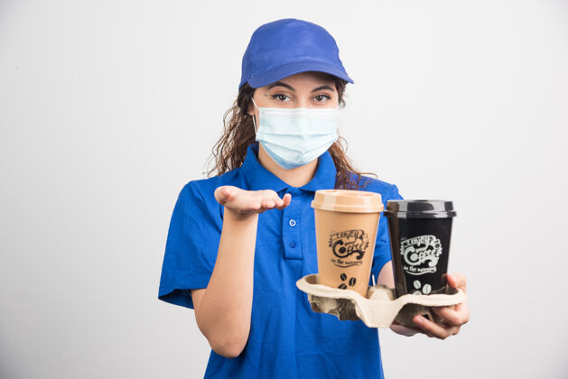 制服一个穿着蓝色制服 戴着医用口罩的女人 手里拿着两杯咖啡咖啡帽子