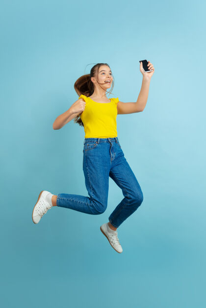 表达少女用智能手机跳得高高的人肖像快乐