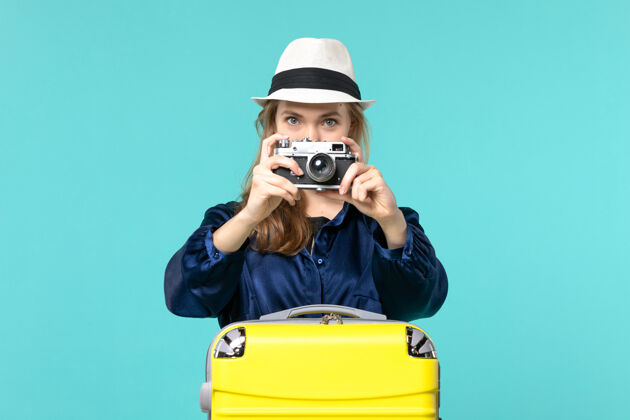 肖像前视图年轻女子拿着相机 在蓝色背景上拍摄女子海上旅行飞机旅程年轻女子旅行