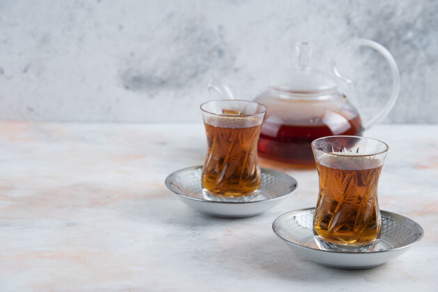 复制空间茶壶和玻璃两杯茶在白色的表面大理石芳香玻璃