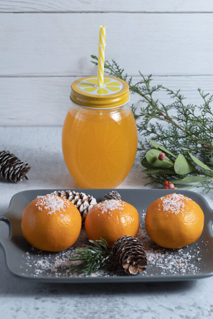 柑橘一盘用粉末和松果装饰的多汁橘子和一罐果汁高质量的照片稻草水果有机