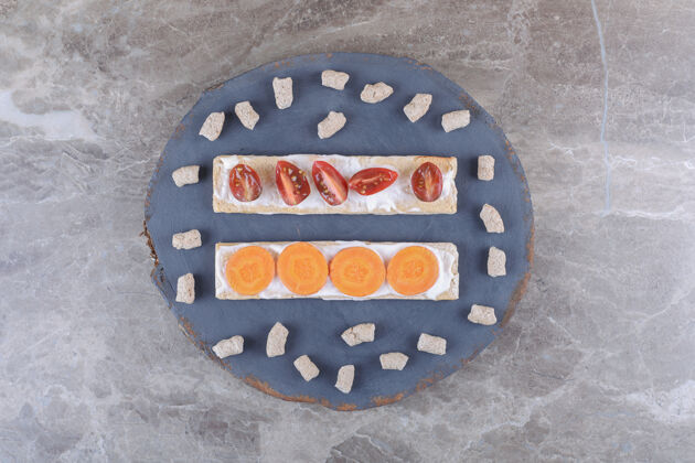 胡萝卜胡萝卜片 西红柿面包片 面包屑包在木板上 大理石表面面筋健康梨