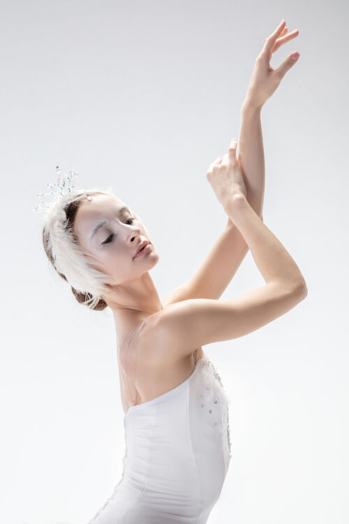 动作以白色工作室为背景的年轻优雅的芭蕾舞演员移动人平衡