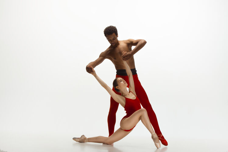 表演优雅的经典芭蕾舞者在白色的工作室背景上独立地跳舞一对穿着鲜红衣服的舞者就像是酒和牛奶的结合优雅 艺术家 动作 动作的概念年轻动作动作