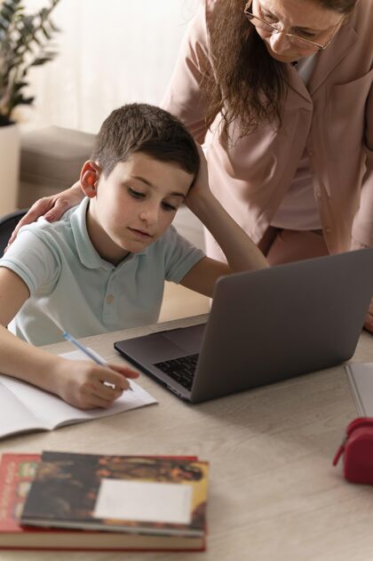 垂直小男孩和奶奶在笔记本电脑上做作业孩子祖母在家