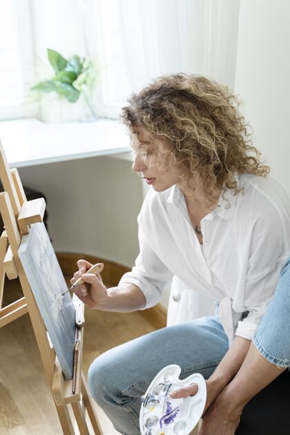 艺术家卷发女子在家画画侧视图内部垂直娱乐