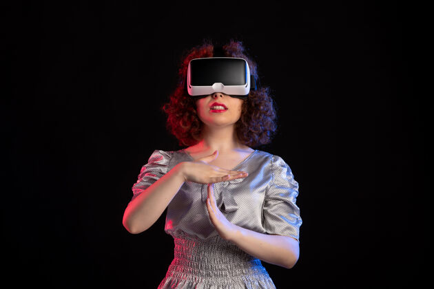 耳机年轻女性戴着虚拟现实耳机在黑暗的表面视觉女人虚拟