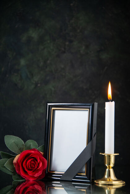 红黑色表面上燃烧着红花的蜡烛的正面图火焰黑暗前面