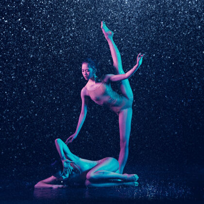 创意两个年轻的女芭蕾舞演员在水滴下情侣霓虹灯成人