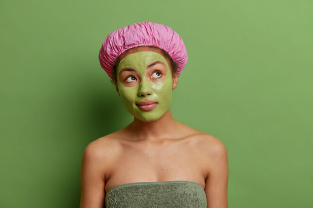 站立深思熟虑的女人集中在脸上戴上绿色的面罩为青春沐浴戴浴巾巾想想身体如何好看享受护肤治疗思维自然护理