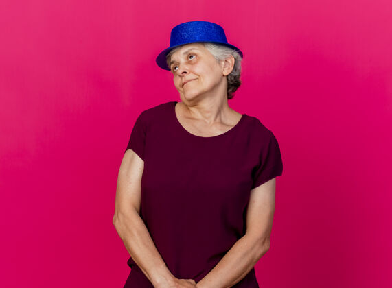 女人高兴的老太婆戴着聚会帽看着旁边的粉红色壁板老人派对