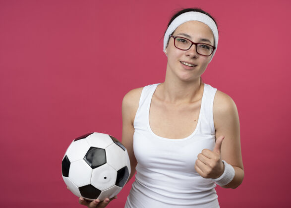 运动戴着眼镜 戴着头带 面带微笑的年轻运动女孩拇指光学头带