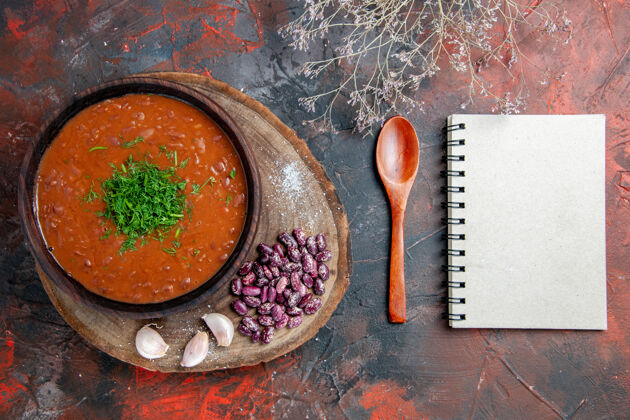 午餐番茄汤豆大蒜切勺和笔记本上的混合色背景俯视图勺子豆类混合物