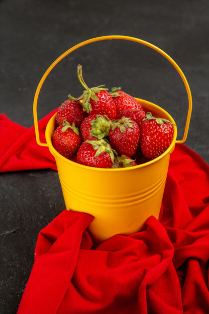 深色正面图新鲜的红色草莓在黑暗背景下的小篮子里草莓树浆果