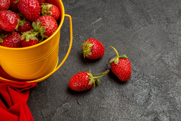 可食用水果正面图新鲜的红色草莓在黑暗背景下的小篮子里新鲜草莓树