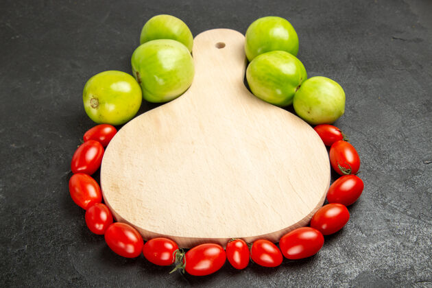 水果底图绿色和红色的西红柿围绕着一个砧板在黑暗的背景食物饮食搭扣