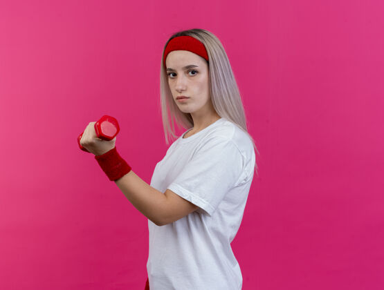 腕带自信的年轻白人运动女孩戴着背带和头带运动背带头带