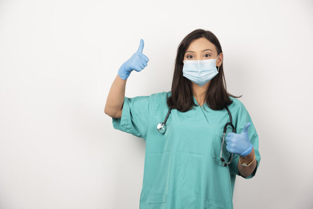 职业戴面具的女医生在白色背景上竖起大拇指高质量照片妇女保健健康
