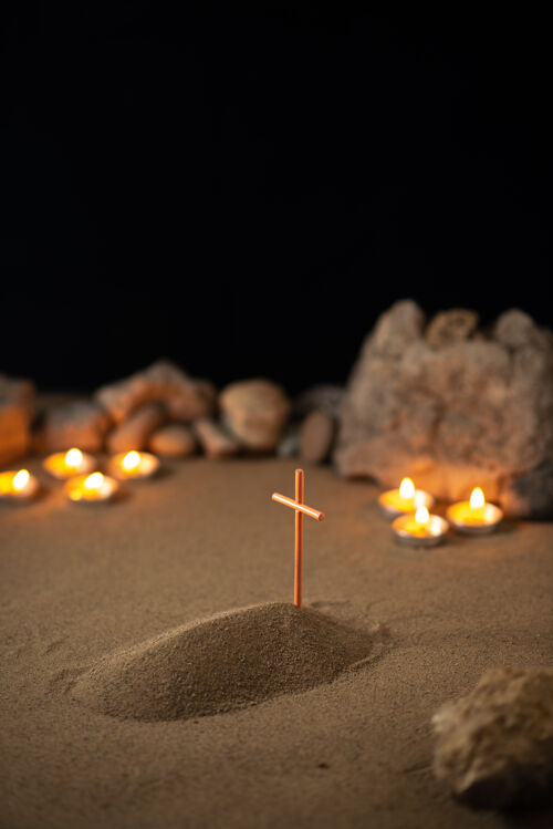 坟墓在黑暗的沙面上用石头和小坟墓点燃蜡烛棍子火葬礼