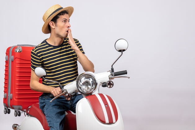 传送带一个戴着草帽 手放在轻便摩托车上的困惑的年轻人的正视图前面轻便摩托车视图