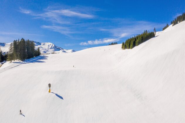 乐趣滑雪区与滑雪者滑下白雪覆盖的斜坡下的蓝天山下雪季节