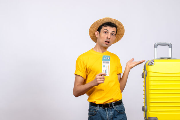 T恤前视图穿着黄色t恤的年轻人指着手提箱休闲前面站