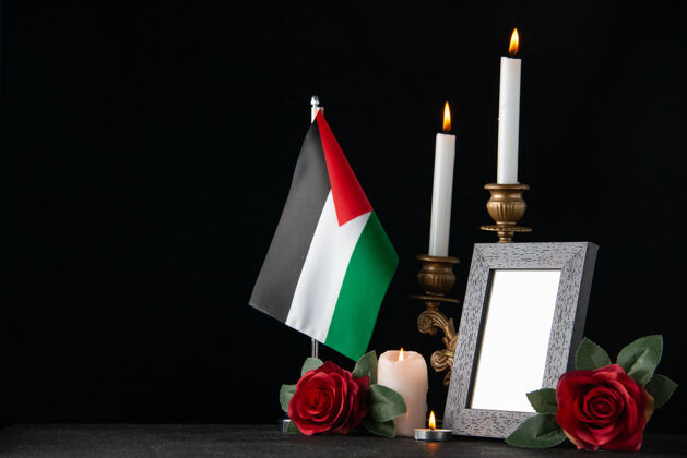 火在黑暗的表面燃烧着巴勒斯坦国旗和鲜花的蜡烛花蜡烛燃烧