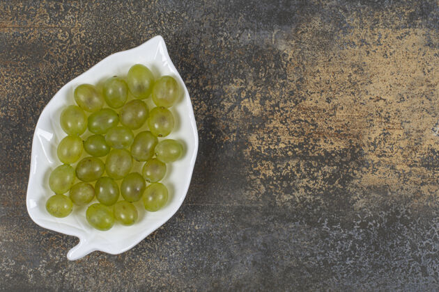 美味新鲜的绿色葡萄放在叶子形状的盘子里成熟一串健康
