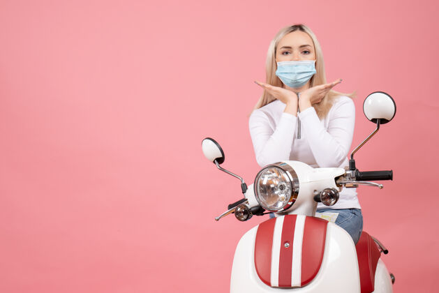 现代前视图：戴着医用面罩的年轻女士站在轻便摩托车旁边医疗轻便摩托车金属