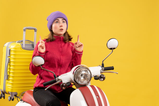 成人前视图：坐在轻便摩托车上的年轻女子手指朝上坐着轻便摩托车车辆