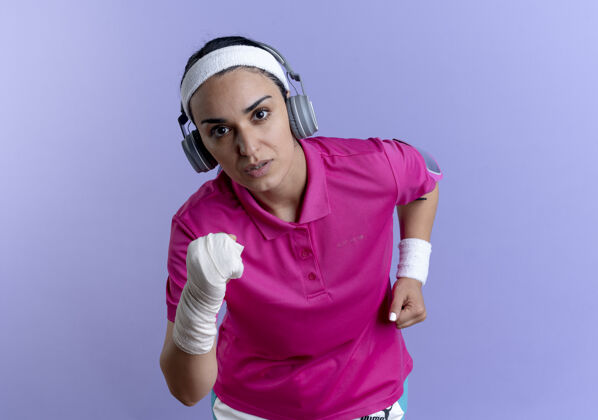 耳机年轻自信的白人运动女性戴着头带和戴着耳机的腕带假装跑步女人白种人紫色
