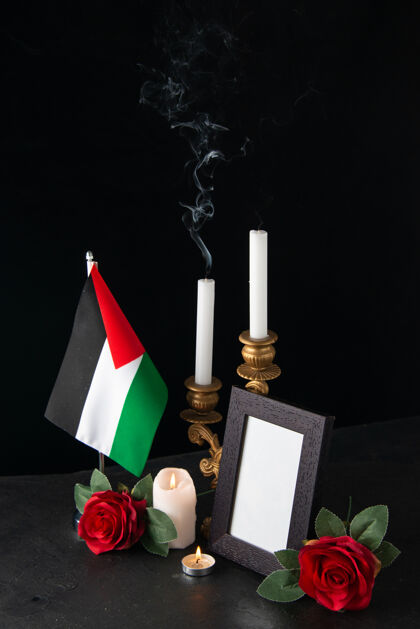花没有火的蜡烛和巴勒斯坦国旗和花在黑暗的表面烛台旗黑