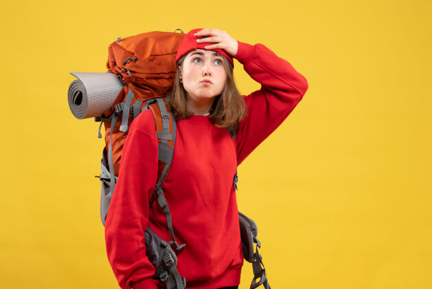 成人正面图：年轻的女旅行者 背着背包 举着头持有青年帽子