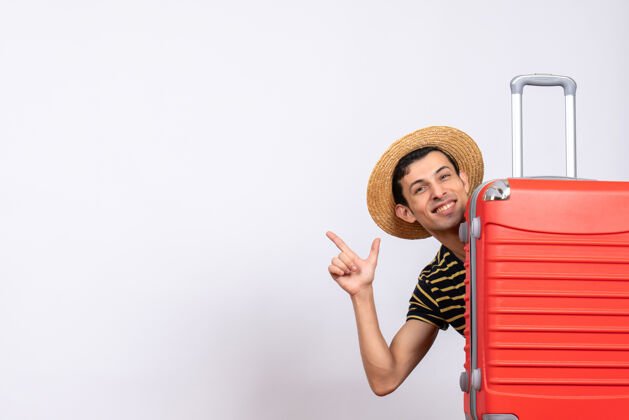 前面正面图：一个戴草帽的年轻人站在红色手提箱后面 指着什么东西吸管年轻人微笑