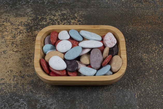 甜点木制盘子上的椭圆形石头糖果五彩岩石石头