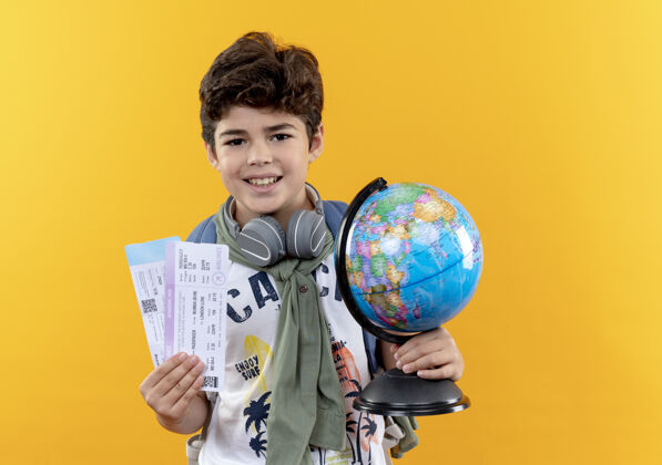 举行微笑着的小男孩 背着书包 戴着耳机 手里拿着票和地球仪微笑学校耳机