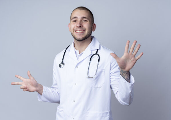 手面带微笑的年轻男医生 身穿医用长袍 脖子上戴着听诊器 显示有三只手和五只手被隔离在白墙上人微笑医学